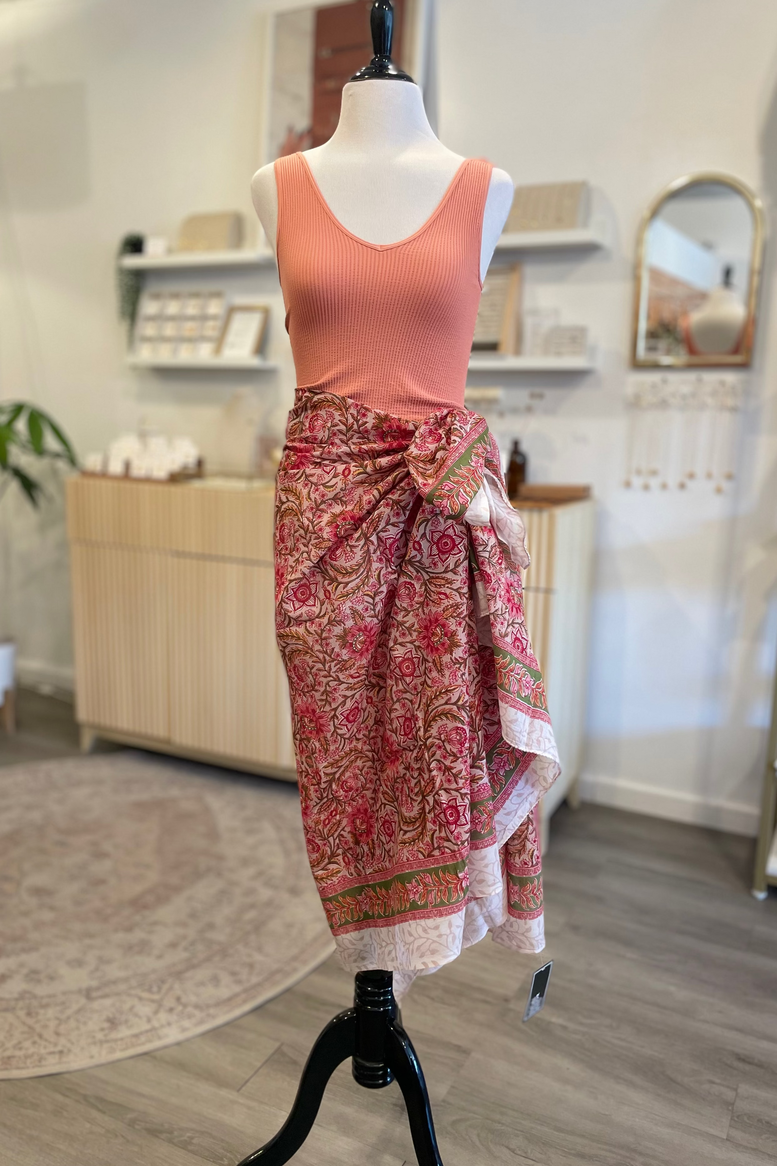 Mannequin wearing a pink top and patterned skirt in a store setting