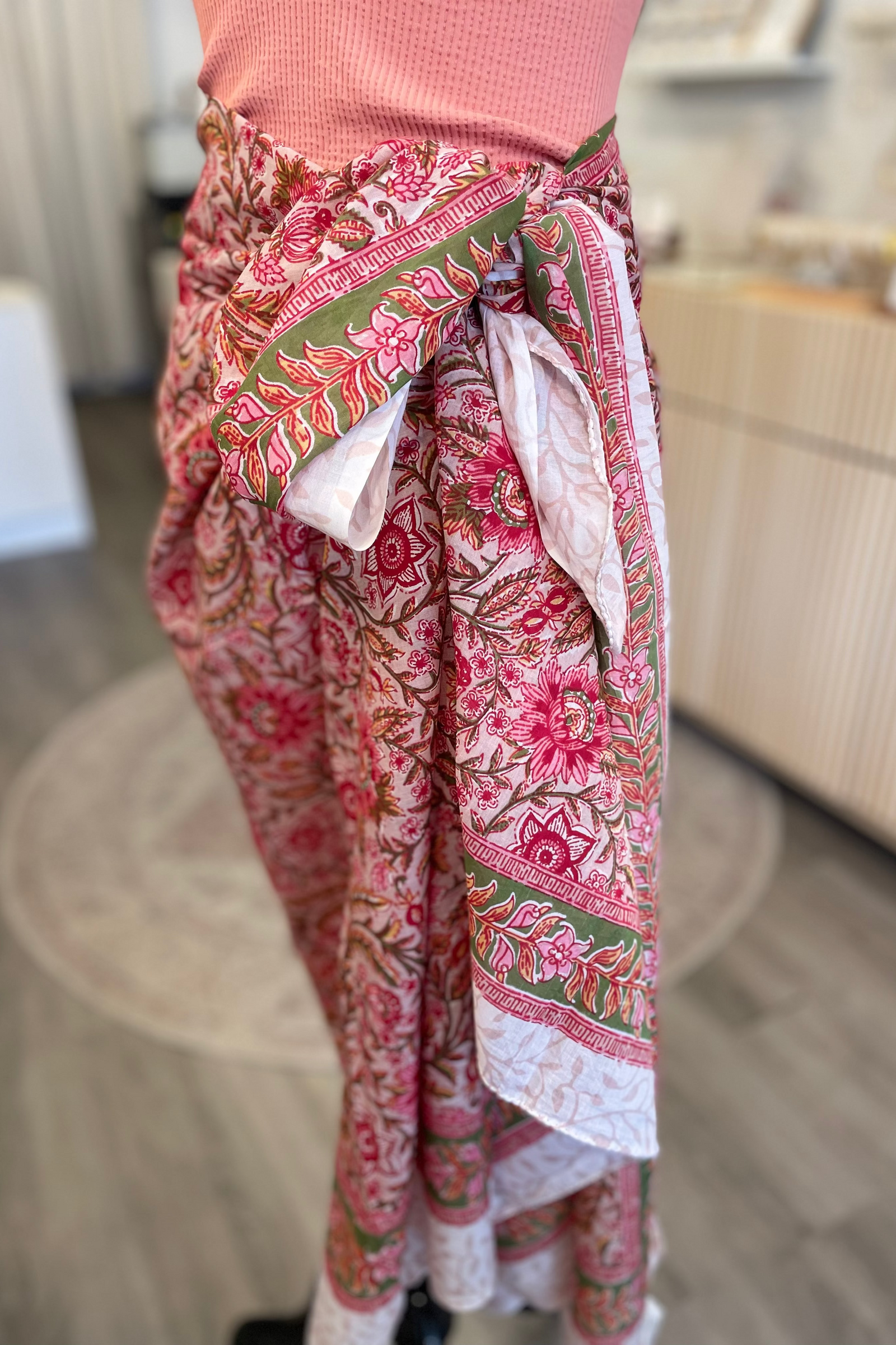 Person wearing a pink floral sarong in an indoor setting