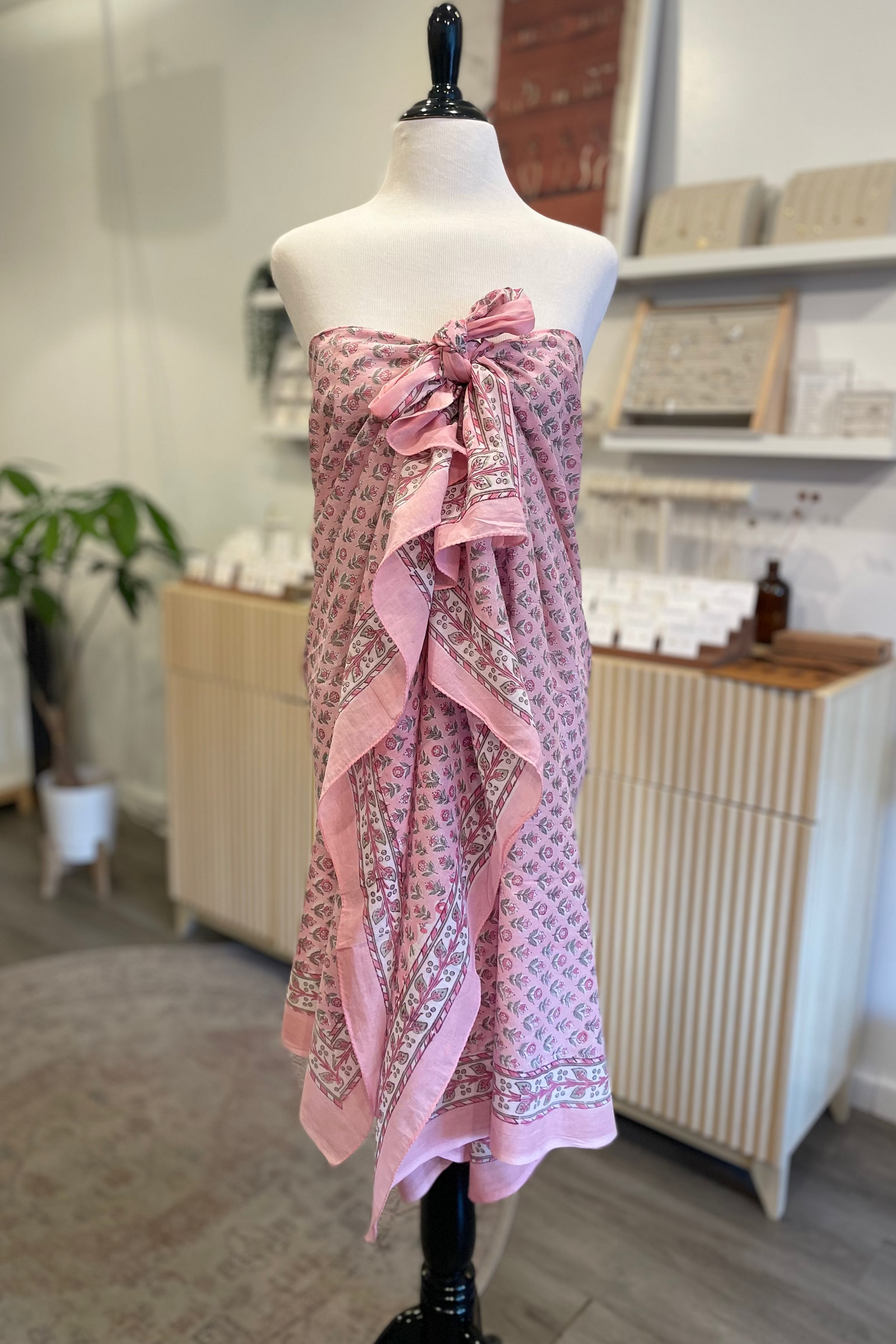 Mannequin wearing a pink patterned dress in a store setting
