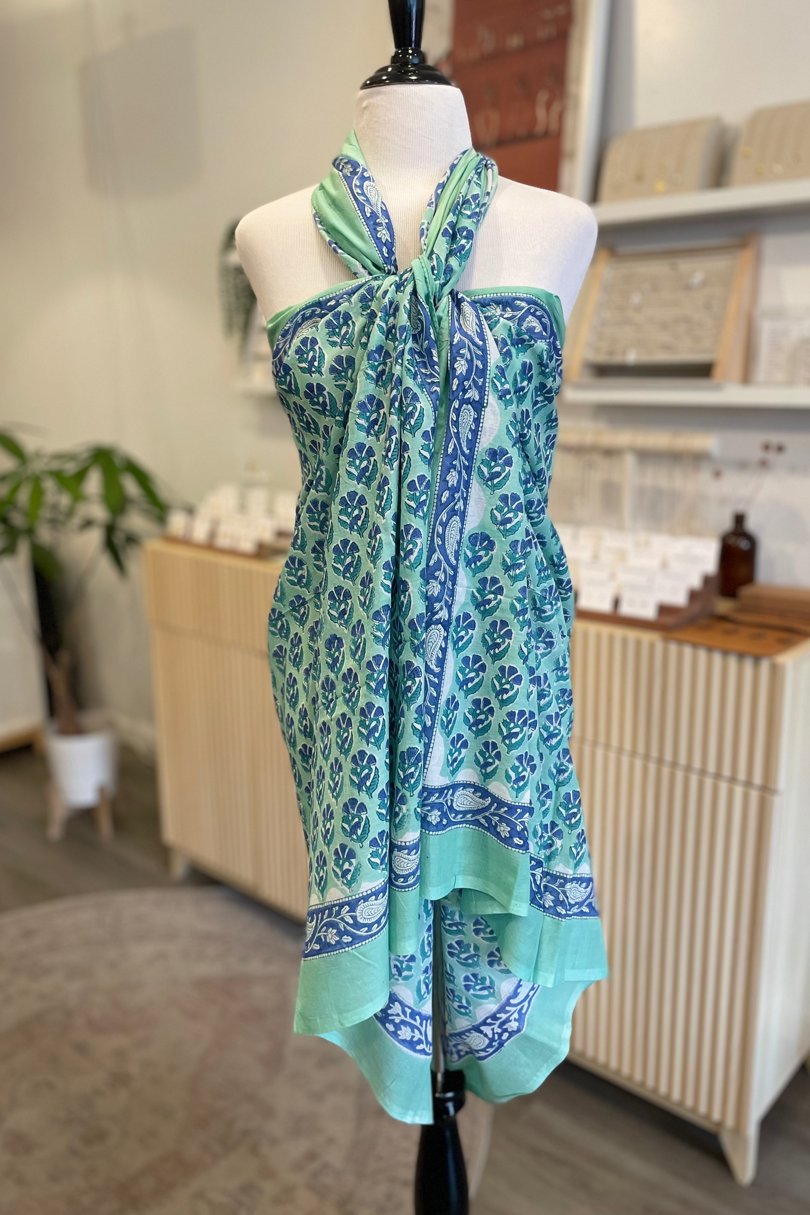 Mannequin wearing a blue and green patterned dress in a room setting.
