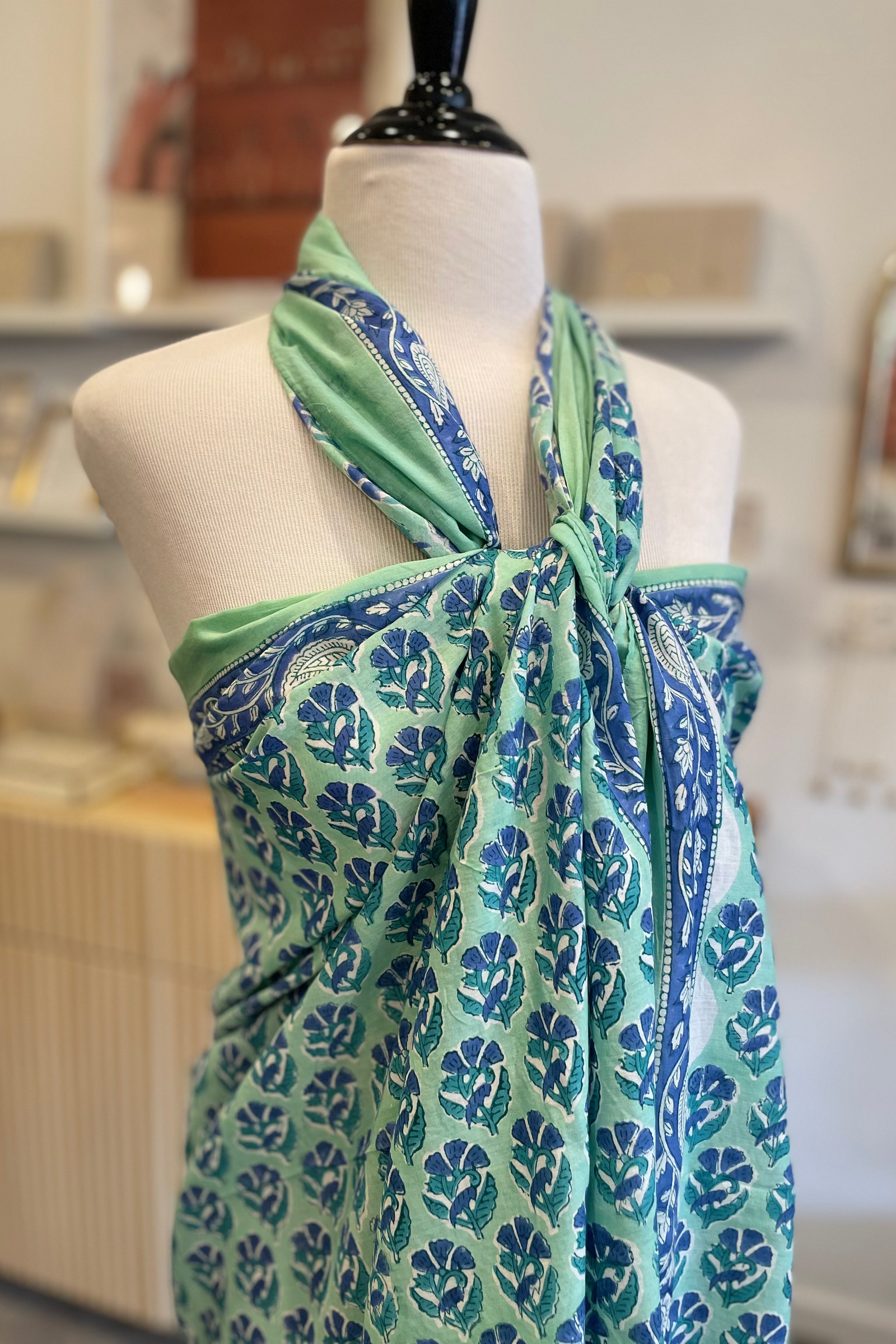Green and blue patterned scarf on a mannequin in a store setting