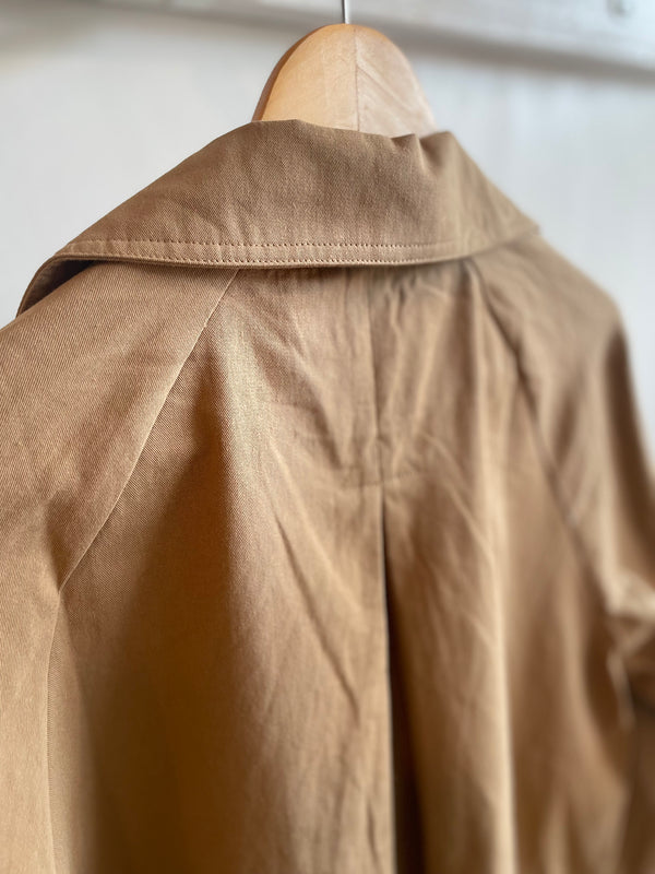 Brown jacket on a hanger against a neutral background