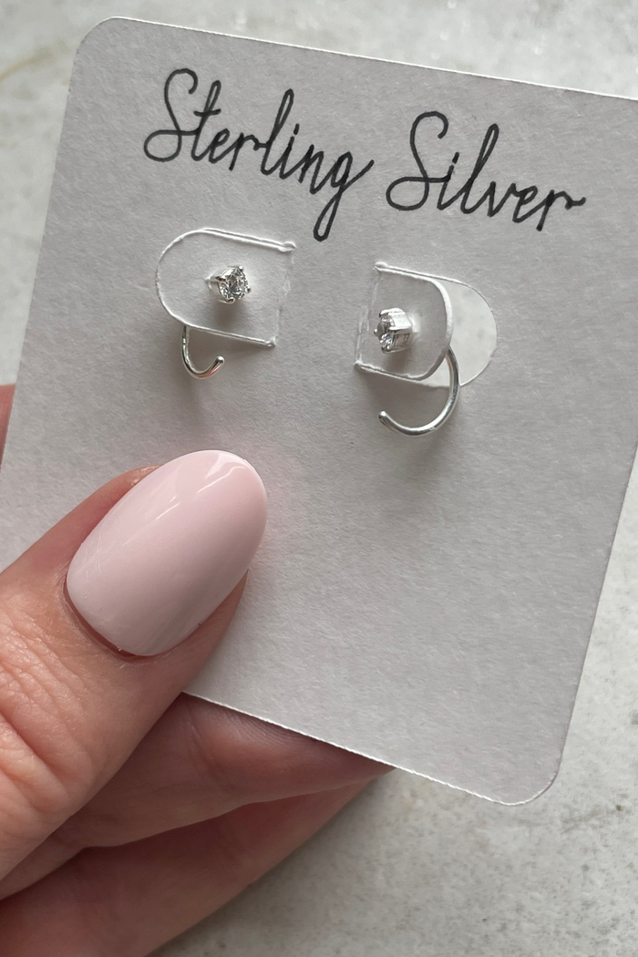  silver 3/4 huggie earrings on a card with 'Sterling Silver' text, held by a hand.