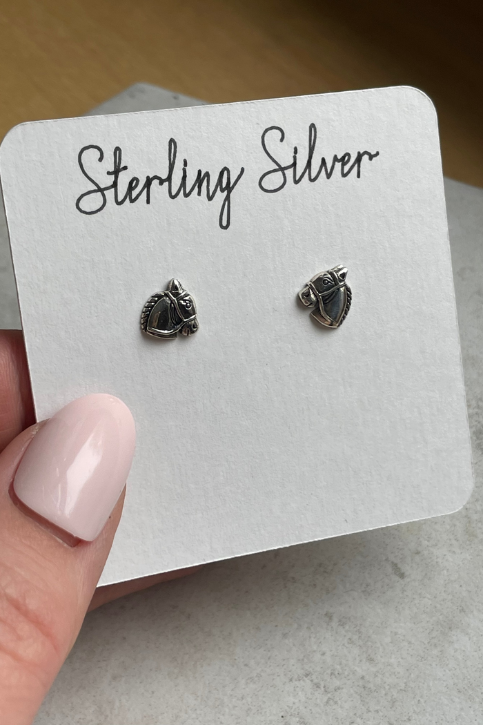 Sterling silver earrings on a display card held by a hand.