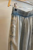 Light blue denim pants hanging on a hanger with a blurred background