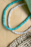 Necklace with blue and white beads on a wooden surface