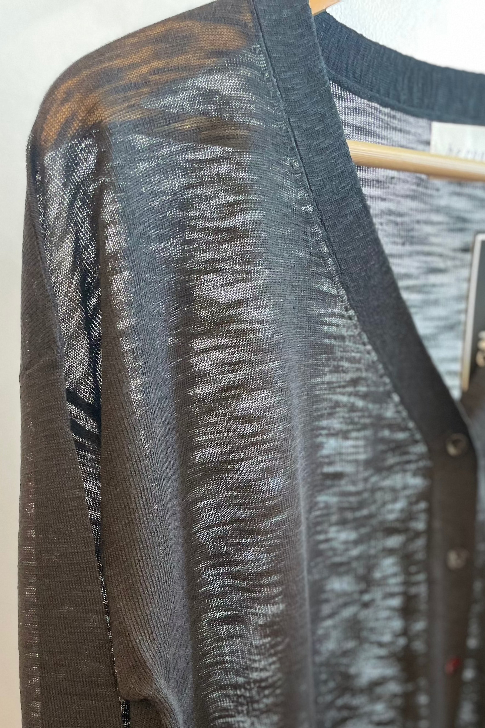 Black sheer cardigan
 top on a hanger with a blurred background