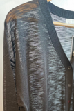 Black sheer cardigan
 top on a hanger with a blurred background