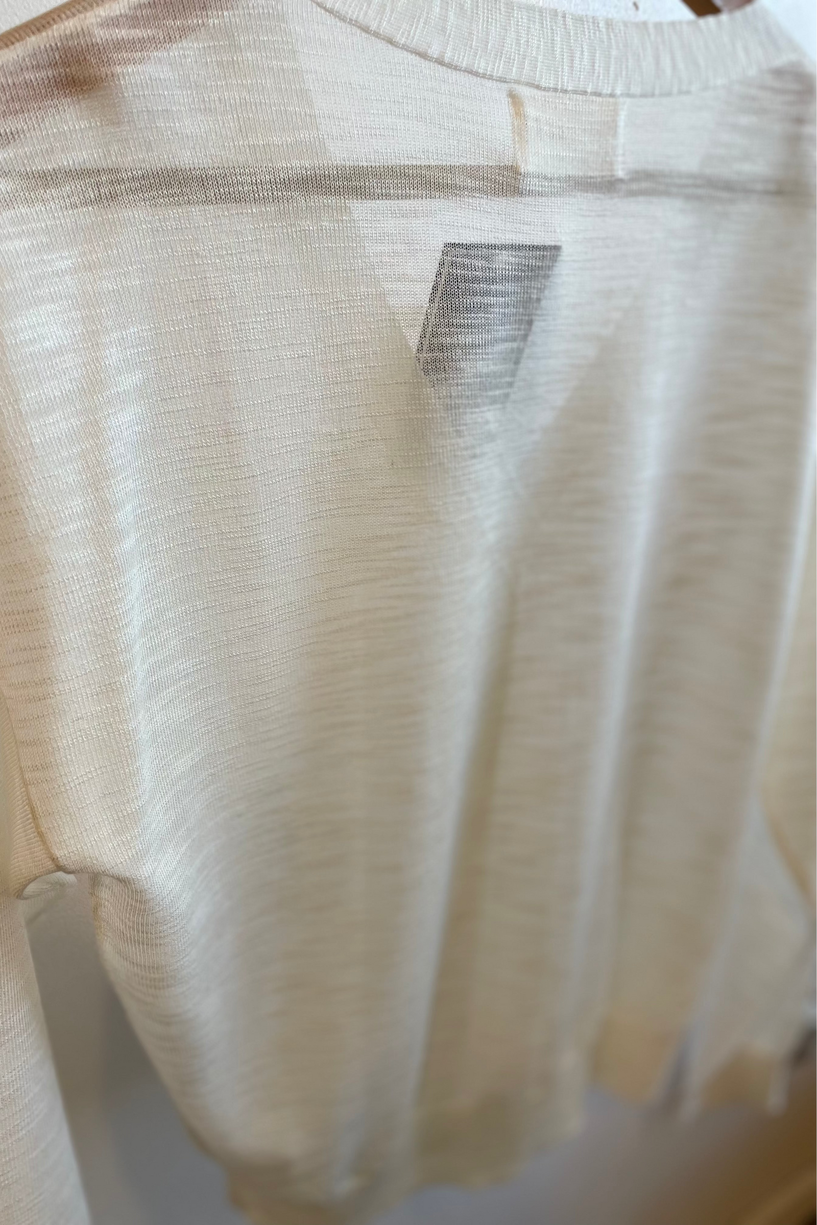 Beige sweater on a hanger with a visible brand label.