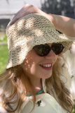 Woman wearing a beige crochet hat and sunglasses outdoors