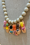 Necklace with white beads and colorful mermaid-themed charms on a textured beige background