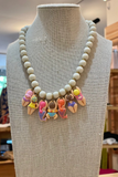 Necklace with white beads and colorful mermaid-themed charms on a mannequin bust.