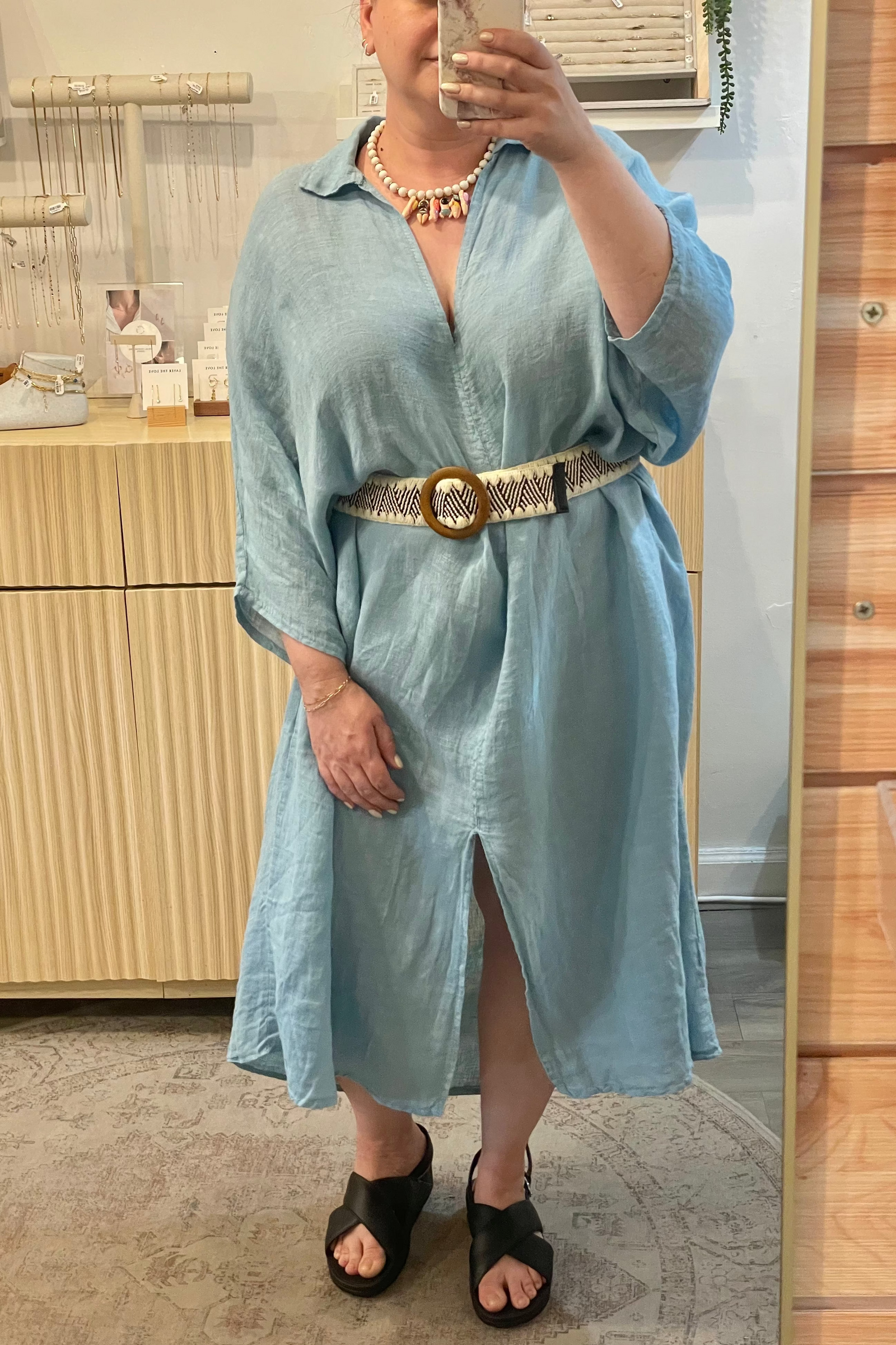 Person wearing a light blue dress with a belt in a boutique setting