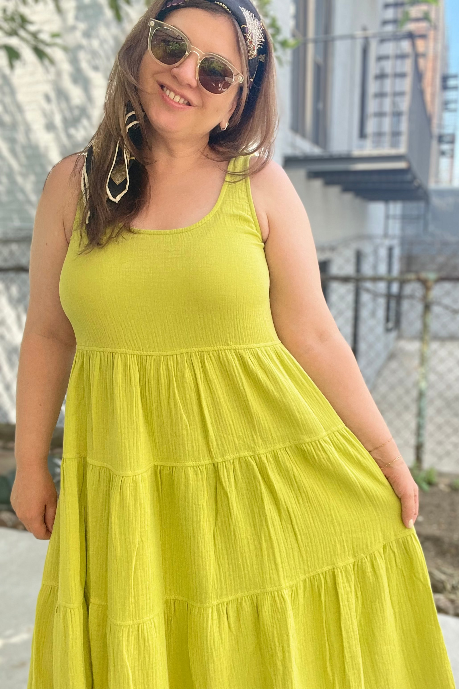 Woman wearing a bright yellow dress with sunglasses and a headband, standing outdoors.