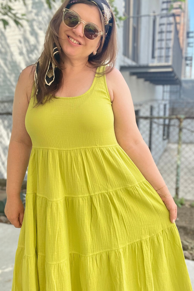 Woman wearing a bright yellow dress with sunglasses and a headband, standing outdoors.
