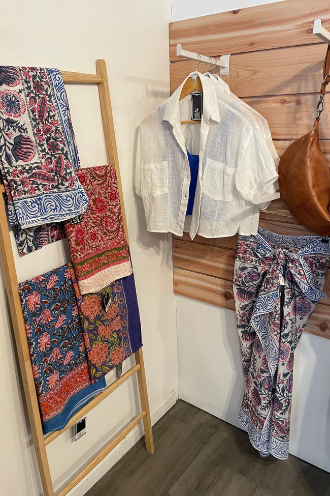 Clothing and accessories on a wooden ladder and hooks in a room.