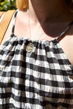 Person wearing a black and white checkered dress with a necklace.