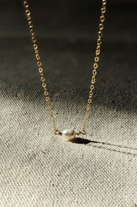 A gold-filled chain necklace with a classic design, featuring a single freshwater pearl pendant.
