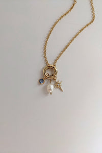 Gold necklace with charms on a light gray background