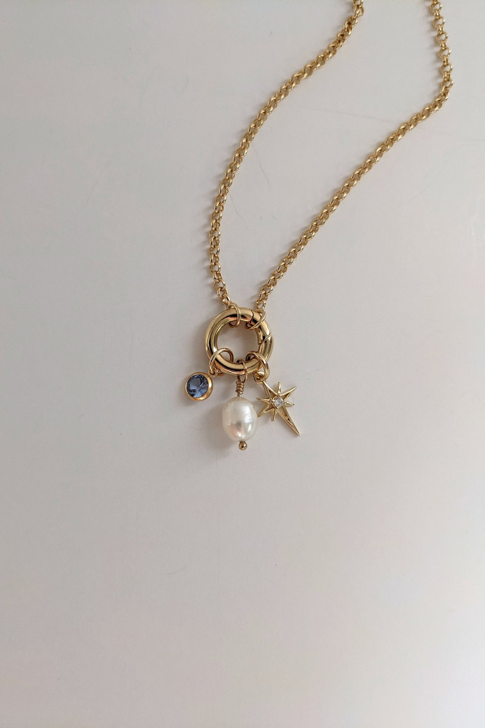 Gold necklace with charms on a light gray background