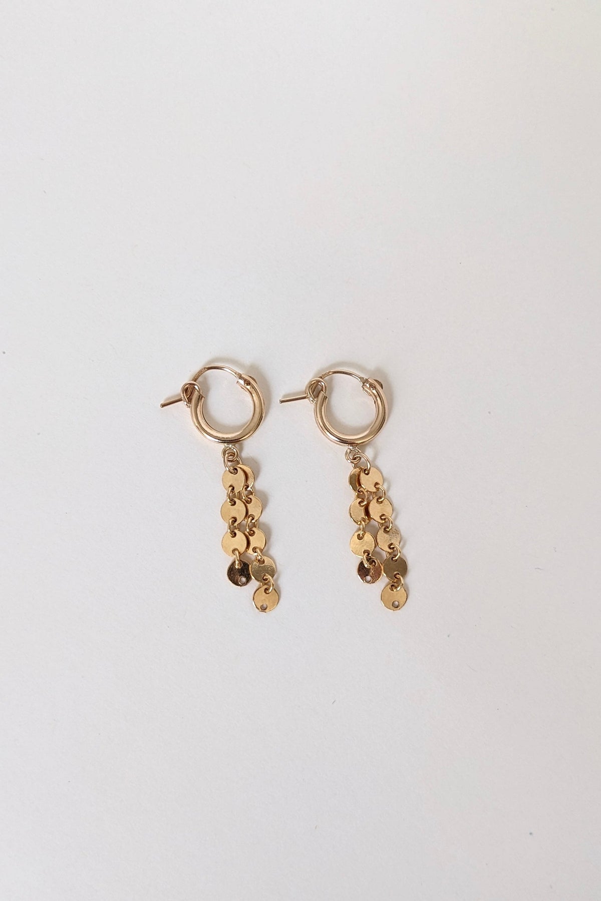 Gold earrings with sequin details on a white background