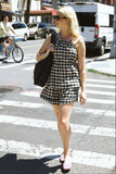 Woman in a checkered short set
 crossing a street with a pedestrian signal.