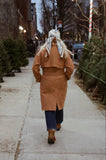 Person walking on a sidewalk with Christmas trees on either side