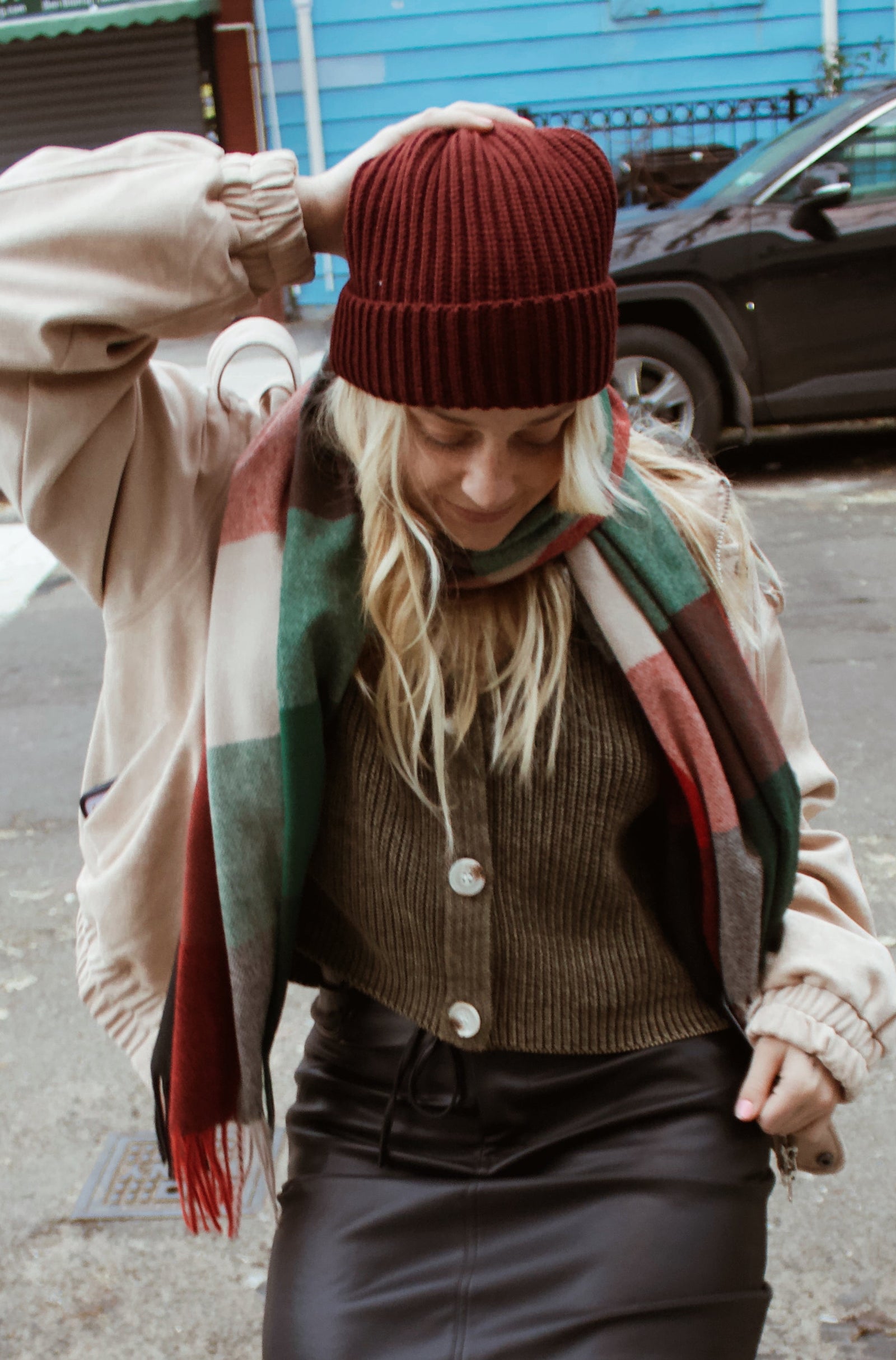 Person wearing a coat, scarf, and patterned tights on a city street.