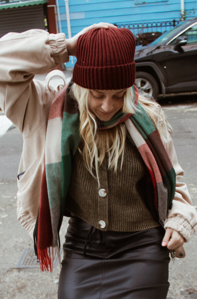 Person wearing a coat, scarf, and patterned tights on a city street.