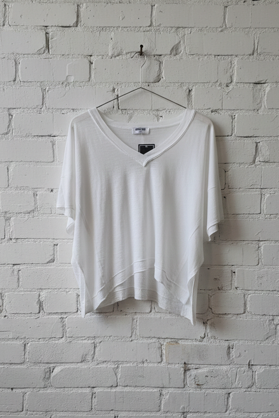 White shirt hanging on a hanger against a white brick wall.