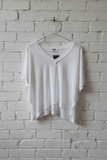 White shirt hanging on a hanger against a white brick wall.