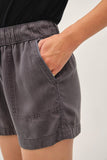 Person wearing dark gray shorts with a plain background