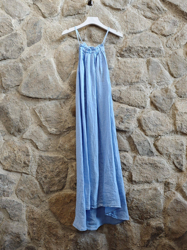 Light blue dress hanging on a hanger against a stone wall