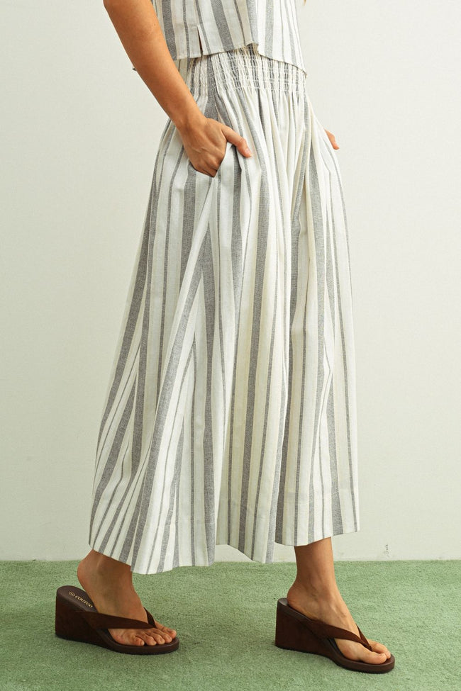 Person wearing a striped outfit with wide-leg pants on a plain background