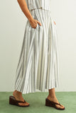 Person wearing a striped outfit with wide-leg pants on a plain background