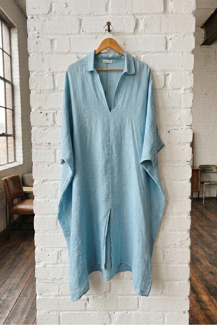 Light blue shirt hanging on a white brick wall in a room with wooden floors and large windows.