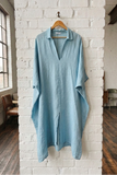 Light blue shirt hanging on a white brick wall in a room with wooden floors and large windows.