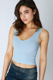 Woman wearing a light blue sleeveless top and denim skirt on a gray background