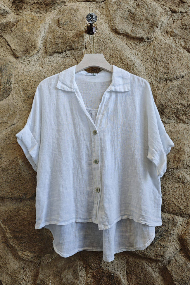 White button-up shirt on a hanger against a stone wall