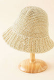 Beige woven bucket hat on a wooden stand against a beige background