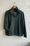 Green pullover on a hanger against a white brick wall