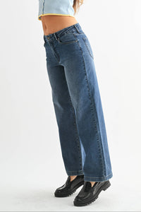Woman wearing a light blue sleeveless top and blue jeans on a white background