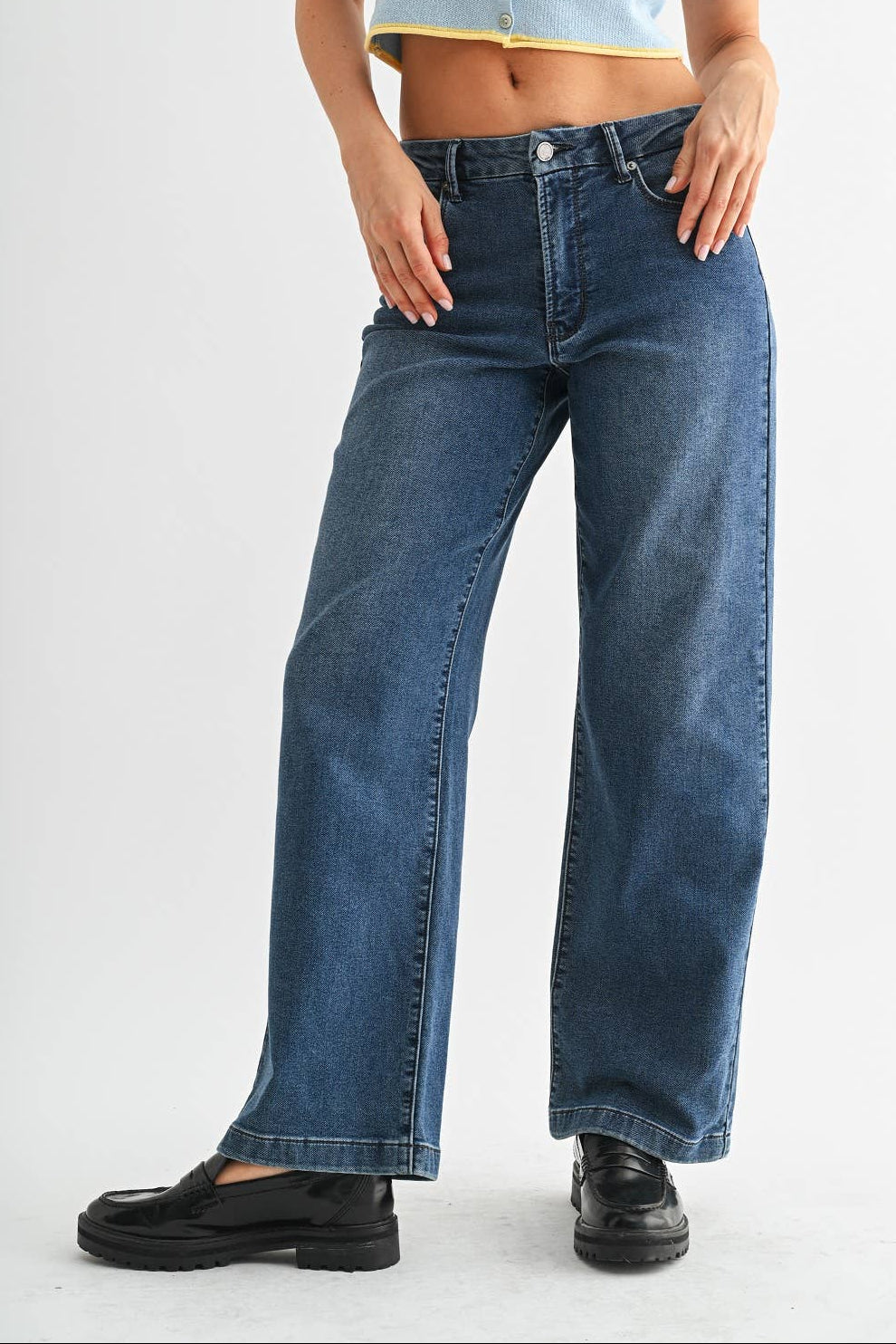 Person wearing blue jeans and a light blue top on a white background