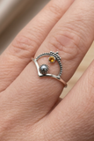 Silver ring with gemstones on a finger against a neutral background