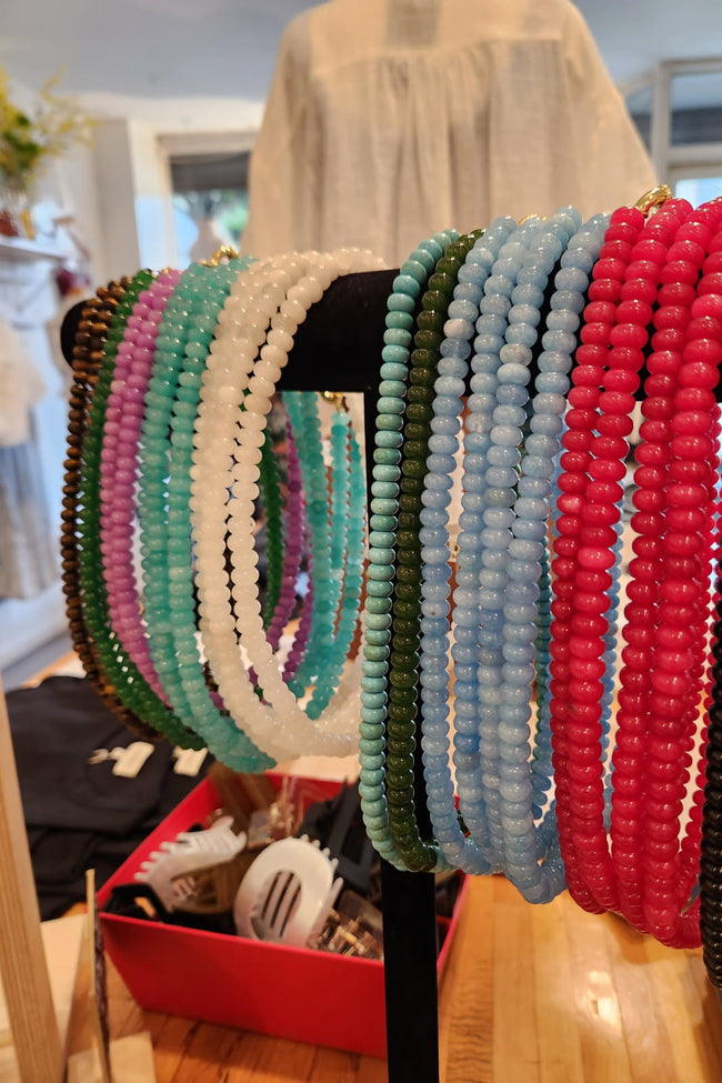 Colorful beaded bracelets on a stand with a blurred indoor background