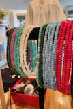 Colorful beaded bracelets on a stand with a blurred indoor background