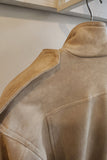 Beige suede jacket on a hanger against a neutral background