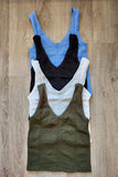 Four tank tops in blue, black, white, and green on a wooden surface