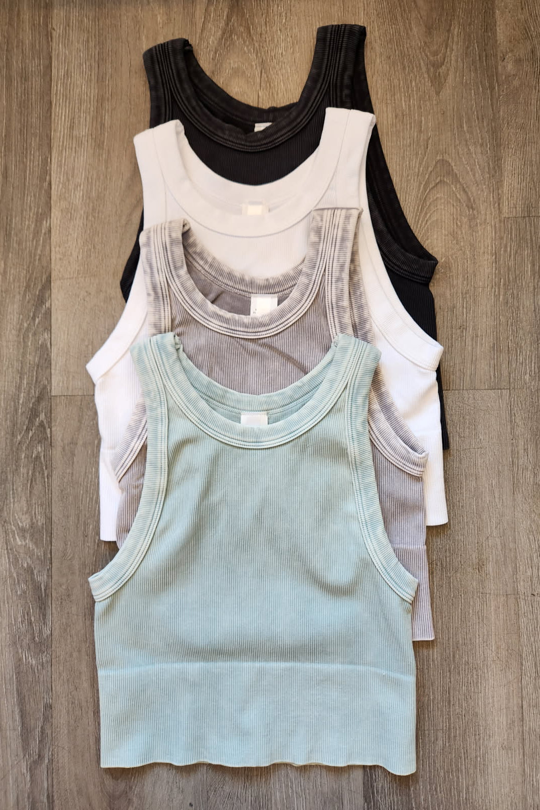 Stack of various tank tops on a wooden surface