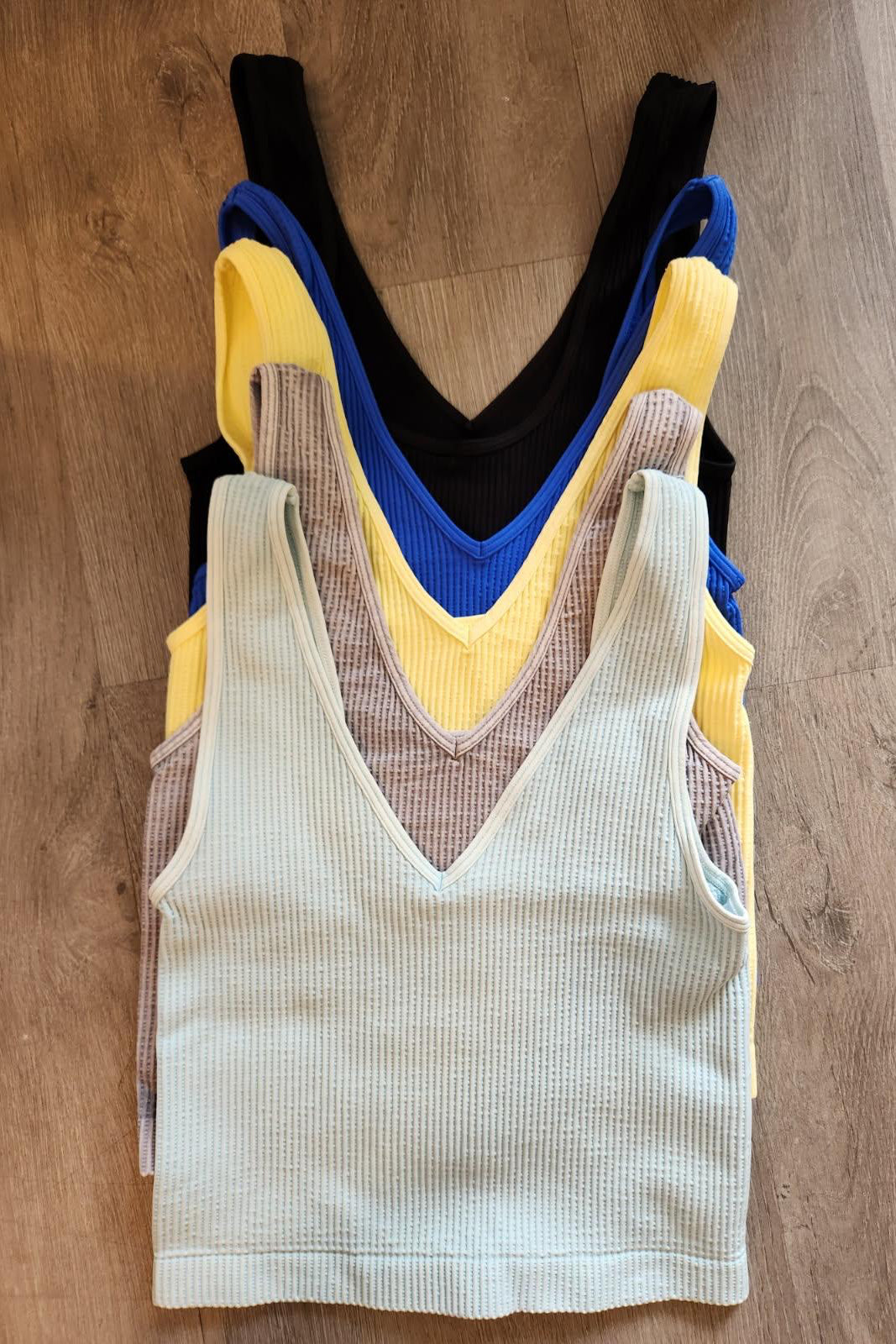 Stack of colorful tank tops on a wooden surface